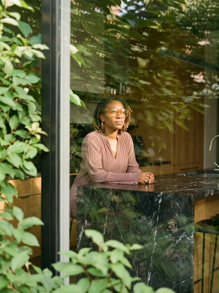 Whitney Herrington seated at a table, framed by green foliage
